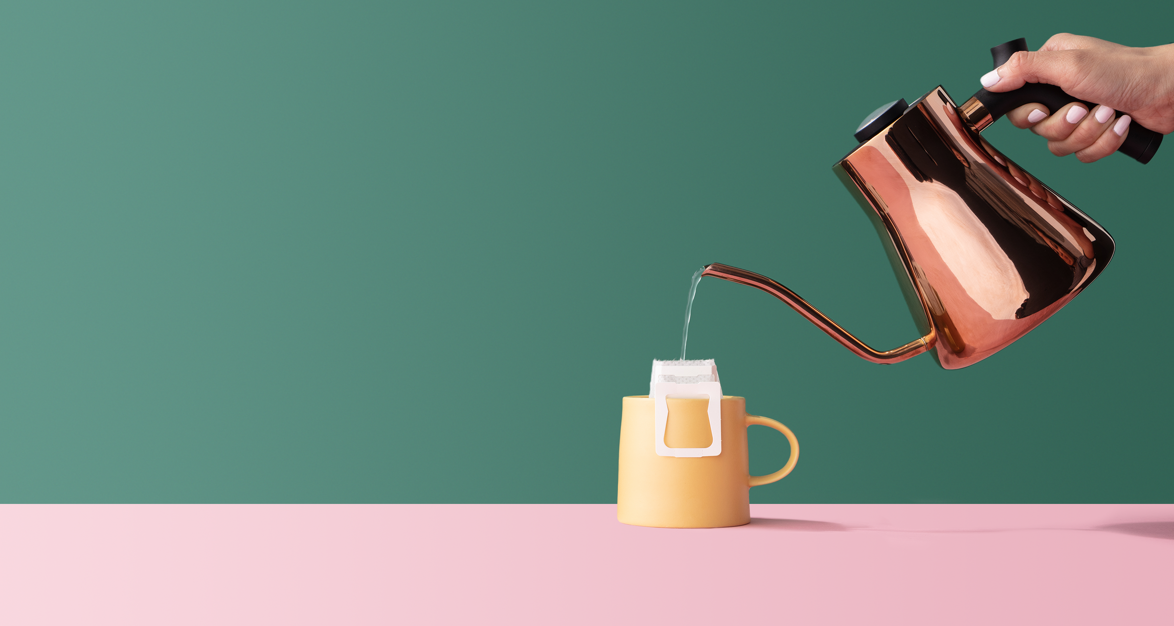 Copper mug pouring hot water into a coffee filter, which is hanging on a yellow mug