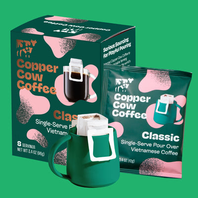Copper Cow Coffee packaging including a box, bag, and green mug on a green background